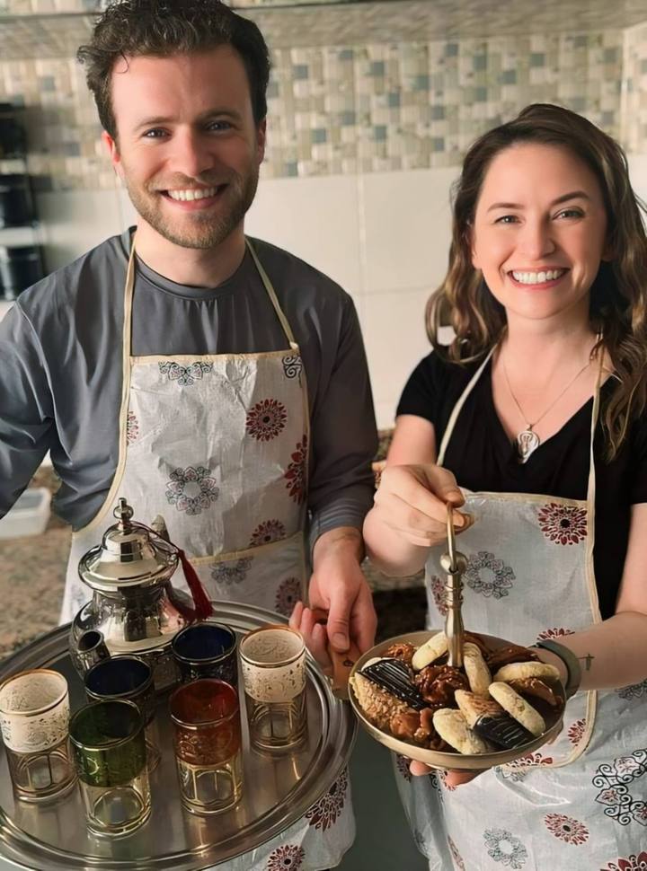 Couple in aprons with a teapot, tea glasses and msemen pancakes