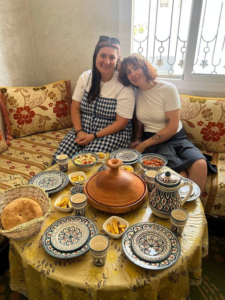 Couple at a round table with a clay tagine, bread and salads