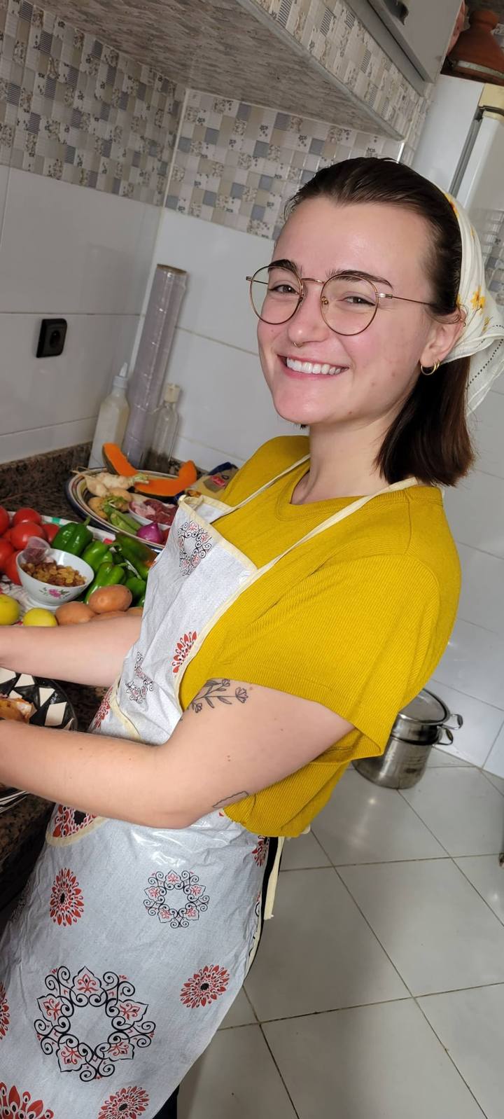 Guest in an apron holding a platter of fresh vegetables in the kitchen