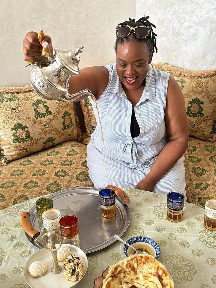 Guest pouring mint tea from a silver teapot into coloured glasses