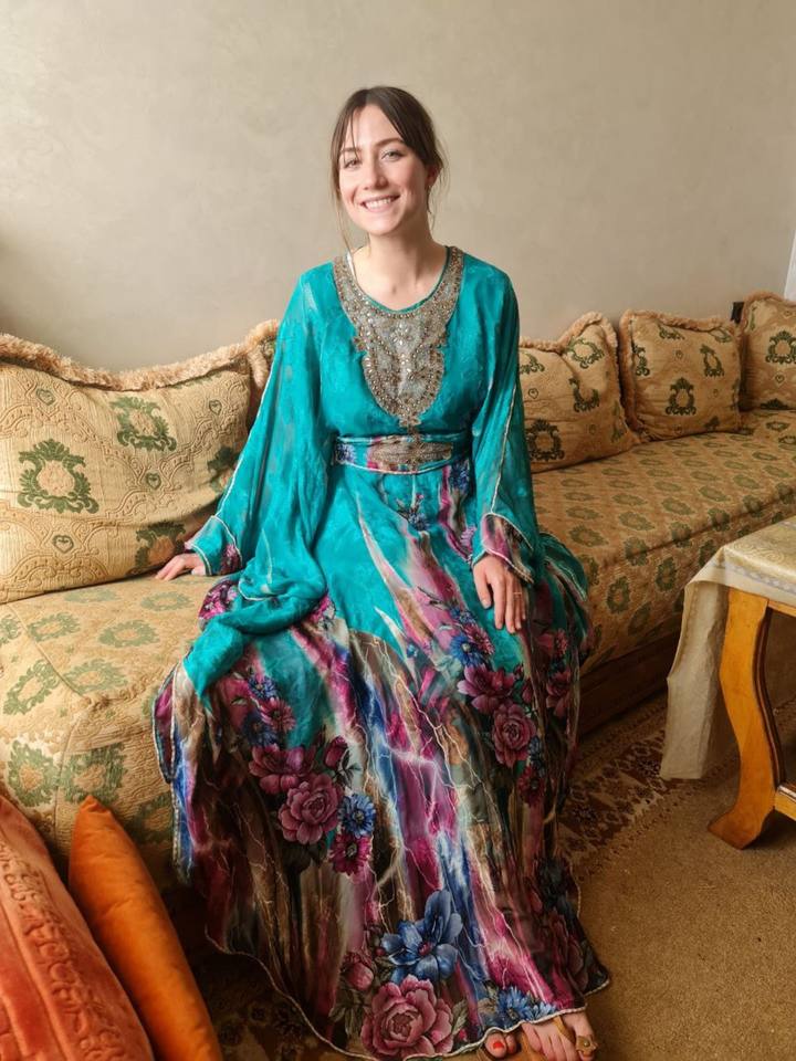 Guest seated in a teal caftan on the salon banquette