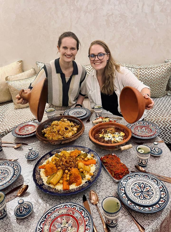 Two guests lifting tagine lids at the dinner table