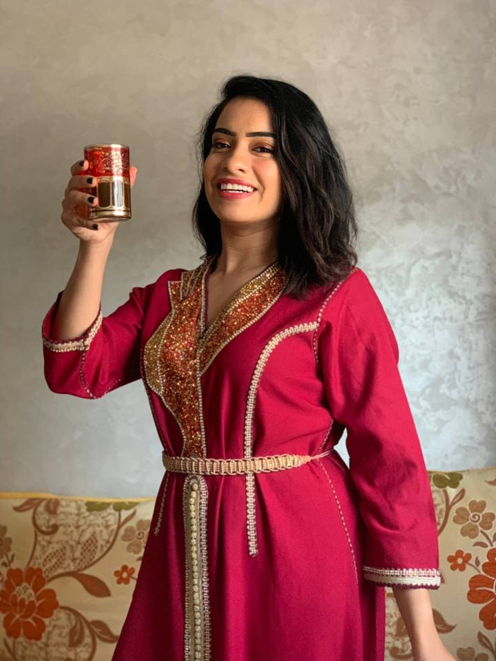 Woman in a red caftan raising a tea glass